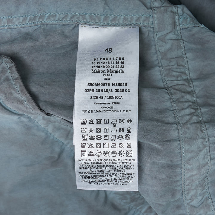 Maison Margiela treated cotton nylon parka coat in mineral-washed grey, featuring an adjustable drawstring hood, front zip with press-stud placket, large flap pockets, and an oversized silhouette with elasticated cuffs