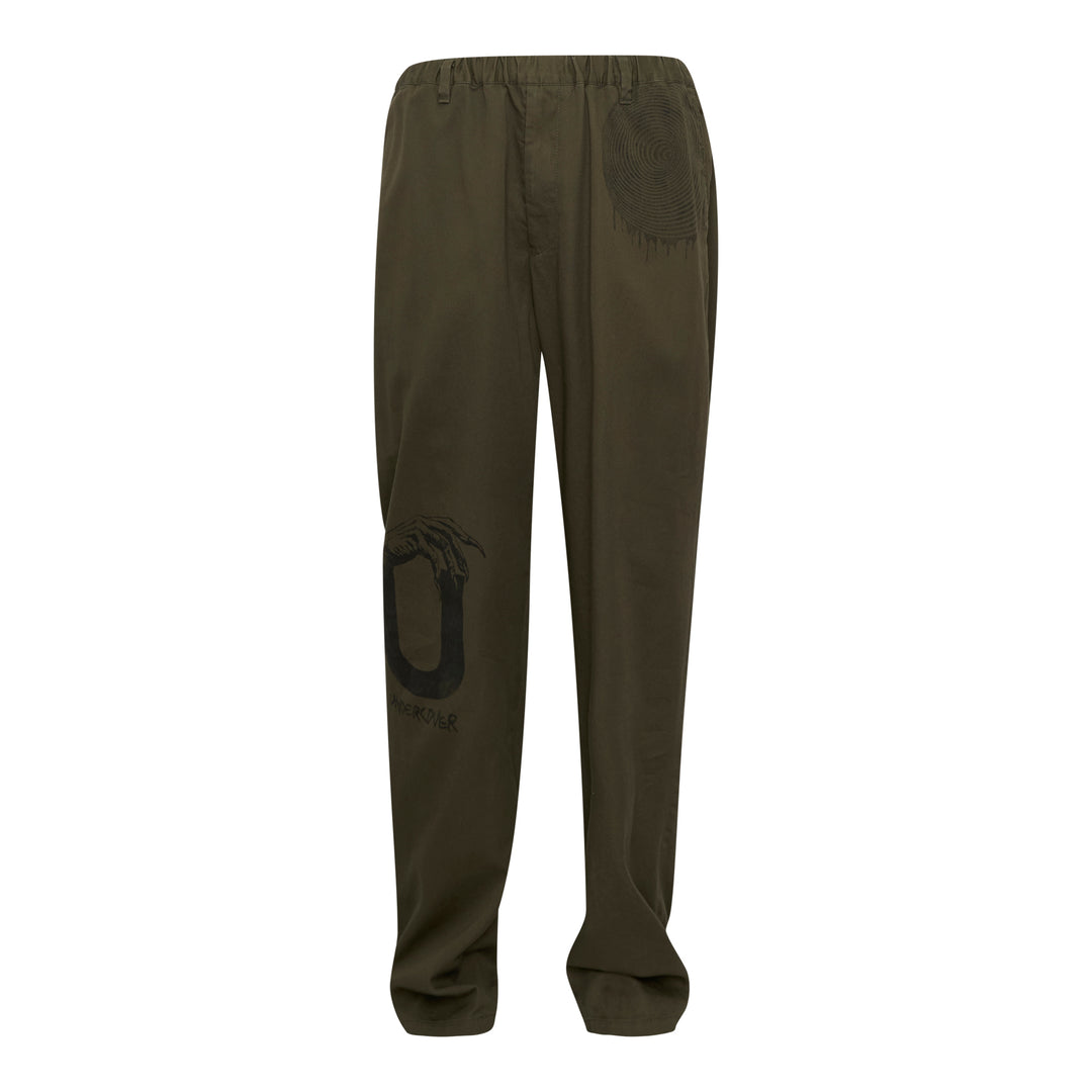 Undercover Witch Hand Elastic Waist Pants in olive green, featuring a tonal black witch claw and serpentine logo graphic on the leg and a concentric spiral drip graphic at the hip, with an elasticated waistband and relaxed wide-leg cut