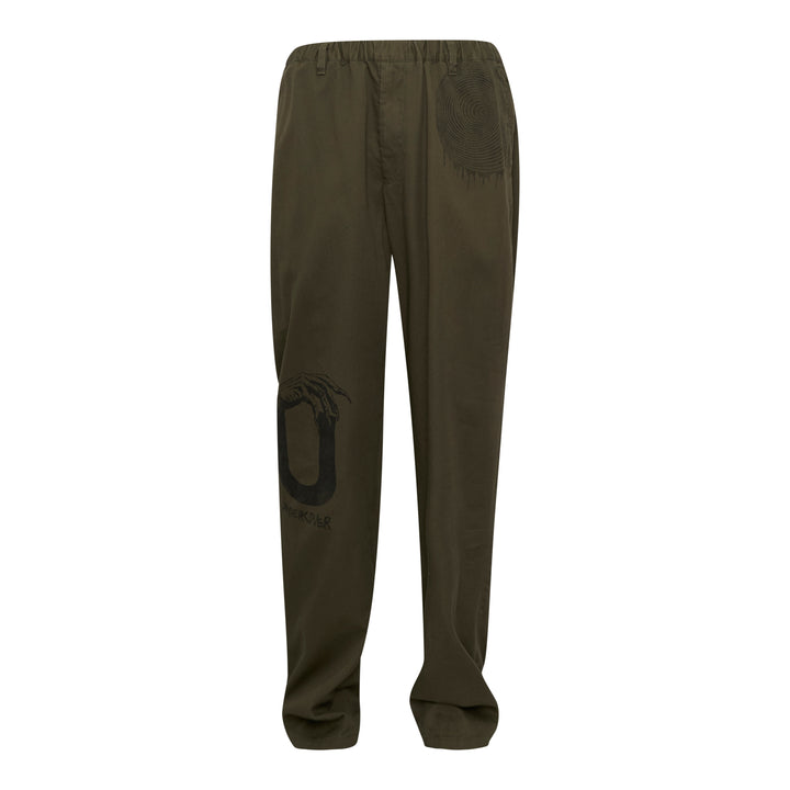Undercover Witch Hand Elastic Waist Pants in olive green, featuring a tonal black witch claw and serpentine logo graphic on the leg and a concentric spiral drip graphic at the hip, with an elasticated waistband and relaxed wide-leg cut