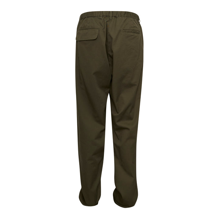 Undercover Witch Hand Elastic Waist Pants in olive green, featuring a tonal black witch claw and serpentine logo graphic on the leg and a concentric spiral drip graphic at the hip, with an elasticated waistband and relaxed wide-leg cut