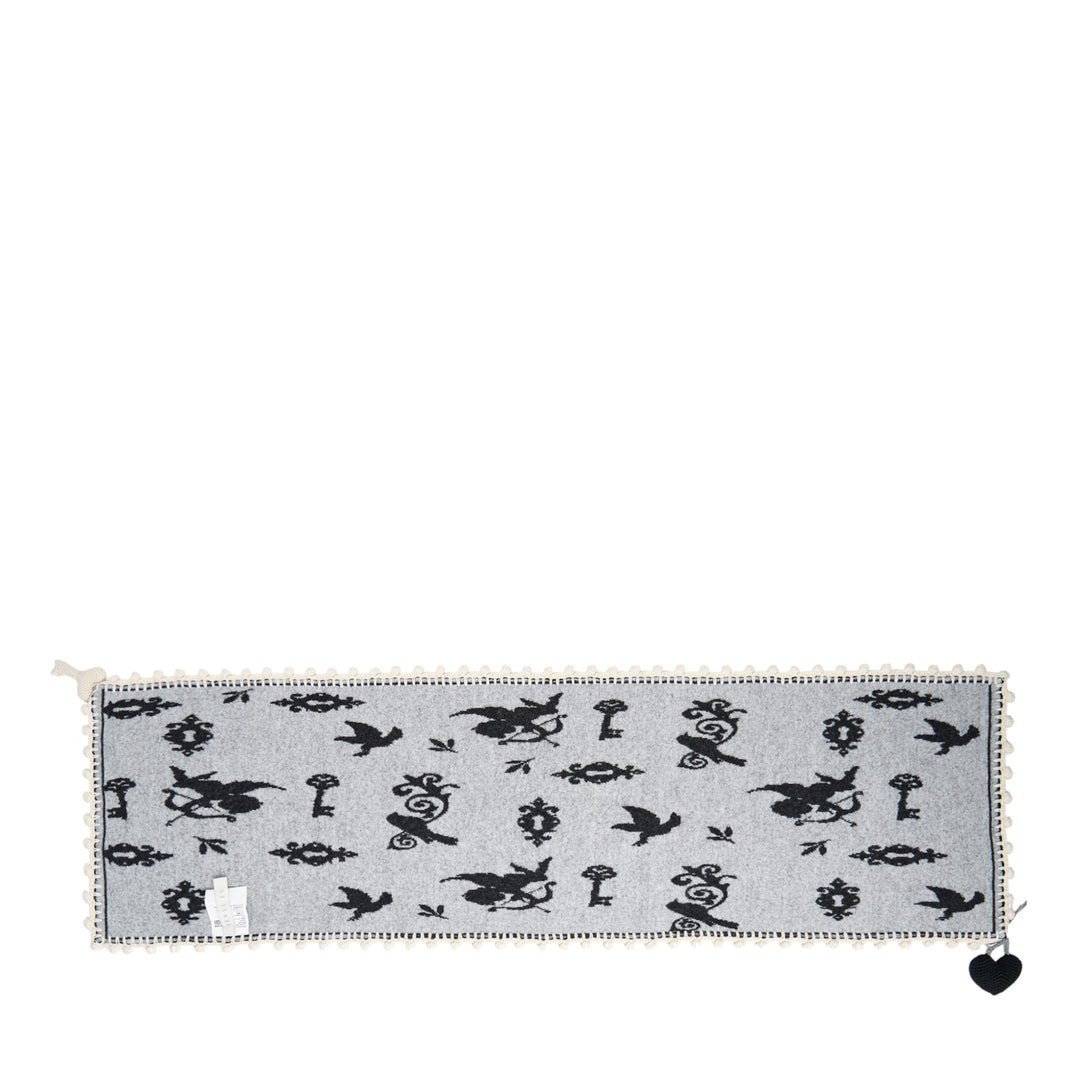Renli Su knit long scarf in dark charcoal with allover ivory bird, key, and lock jacquard motif, finished with a hand-crocheted ivory border and a woven heart charm at the corner - view 2