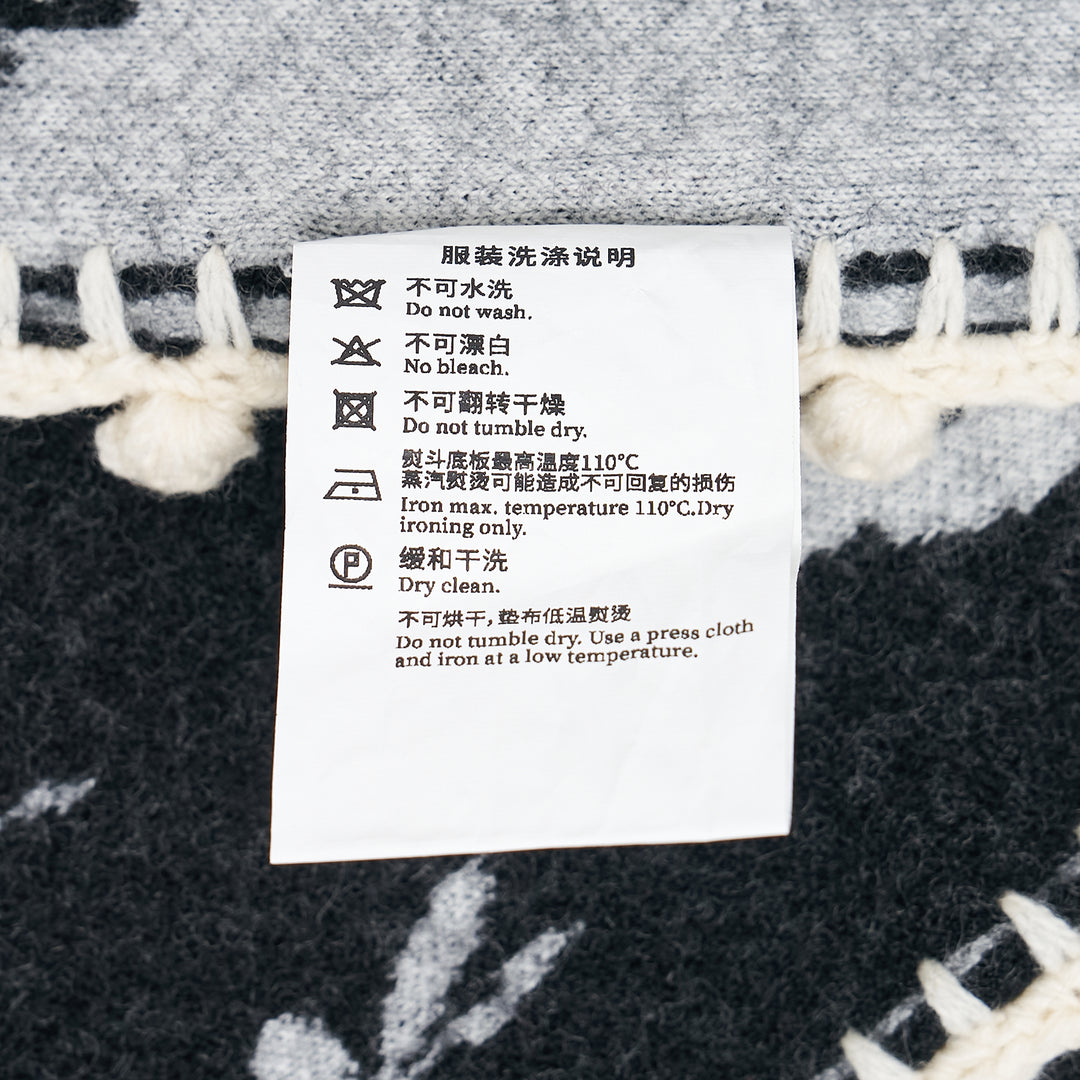 Renli Su knit long scarf in dark charcoal with allover ivory bird, key, and lock jacquard motif, finished with a hand-crocheted ivory border and a woven heart charm at the corner - view 3