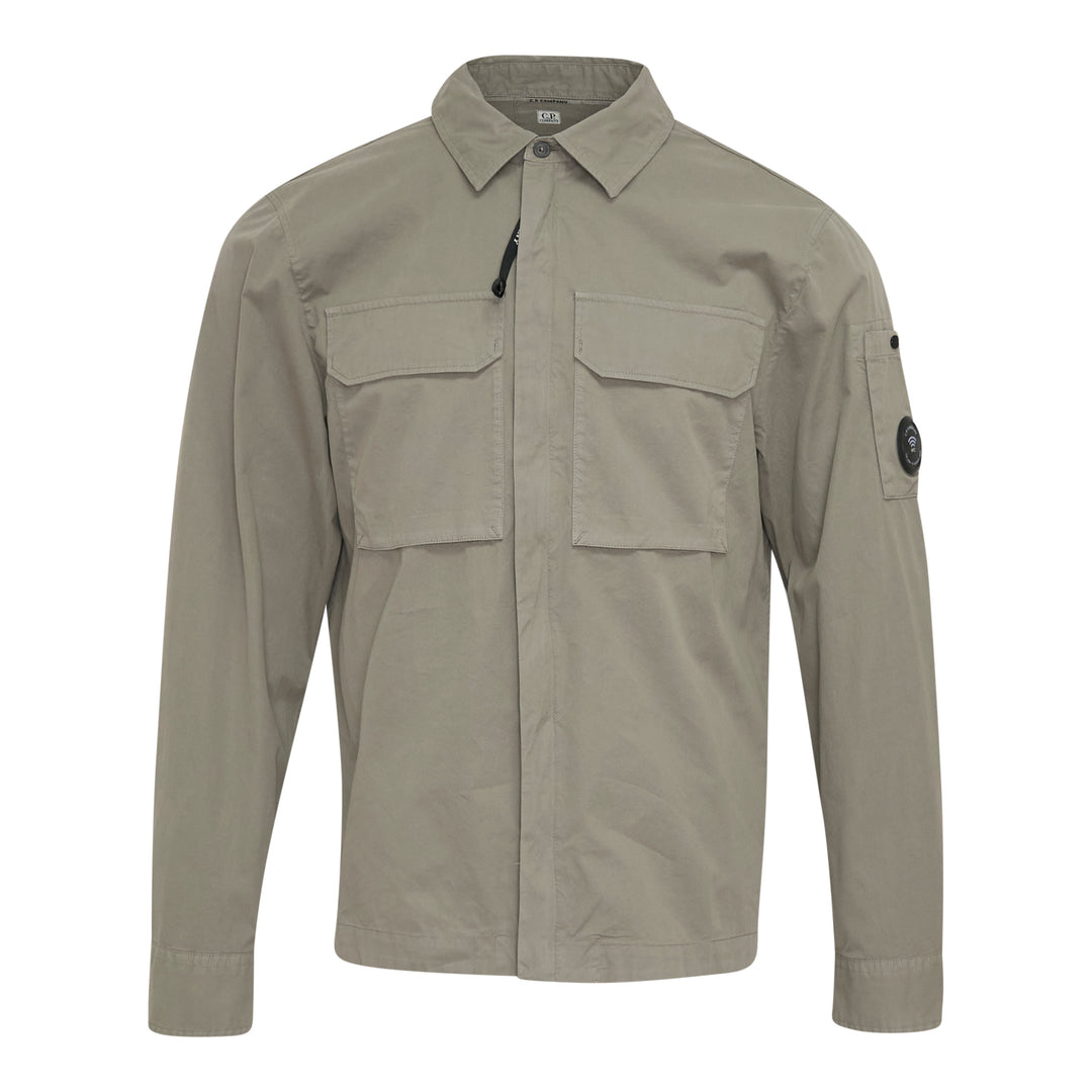 C.P. Company Organic Gabardine Zipped Overshirt in sage green, featuring dual chest flap pockets, concealed zip closure, and signature goggle lens badge on the sleeve