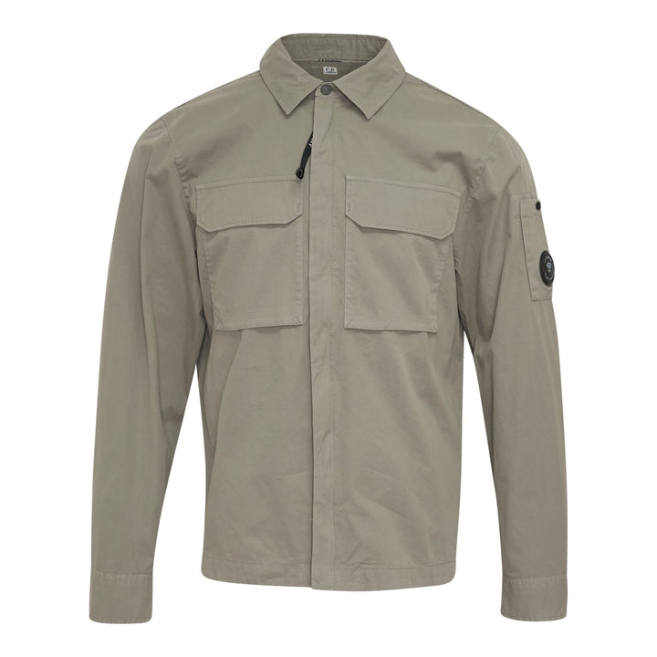 C.P. Company Organic Gabardine Zipped Overshirt in sage green, featuring dual chest flap pockets, concealed zip closure, and signature goggle lens badge on the sleeve