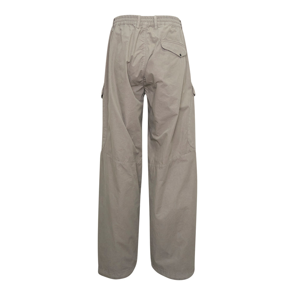 C.P. Company Micro-Reps Boxy Lens Cargo Pants in stone beige, featuring wide-leg silhouette, thigh cargo pockets with snap closures, elasticated waistband, and signature circular lens badge on the outer leg