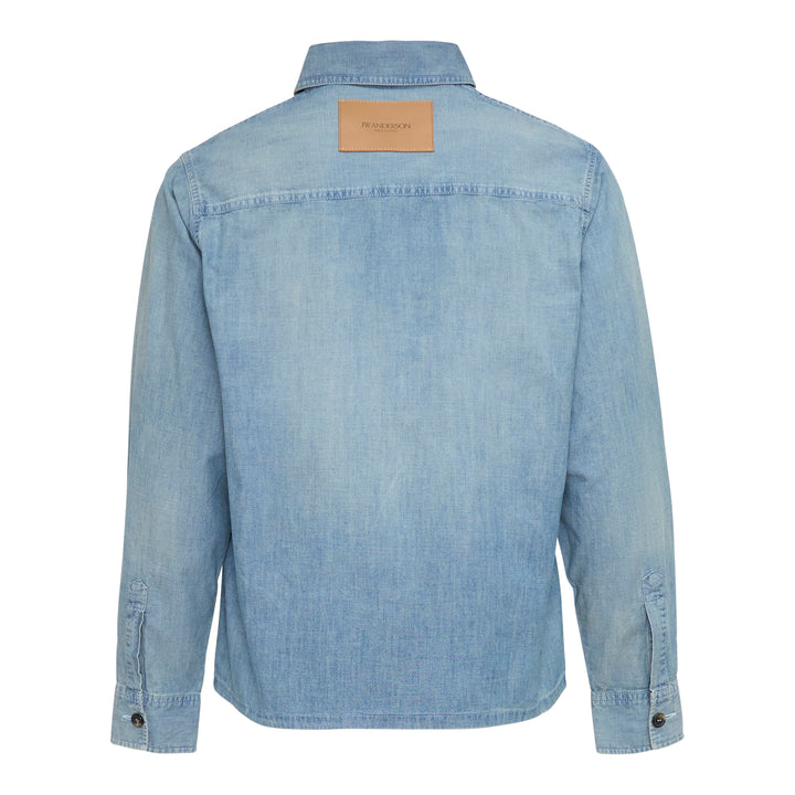 JW Anderson Slant Pocket Chambray Shirt in washed light blue denim, featuring a point collar, button-front closure, and a patch chest pocket
