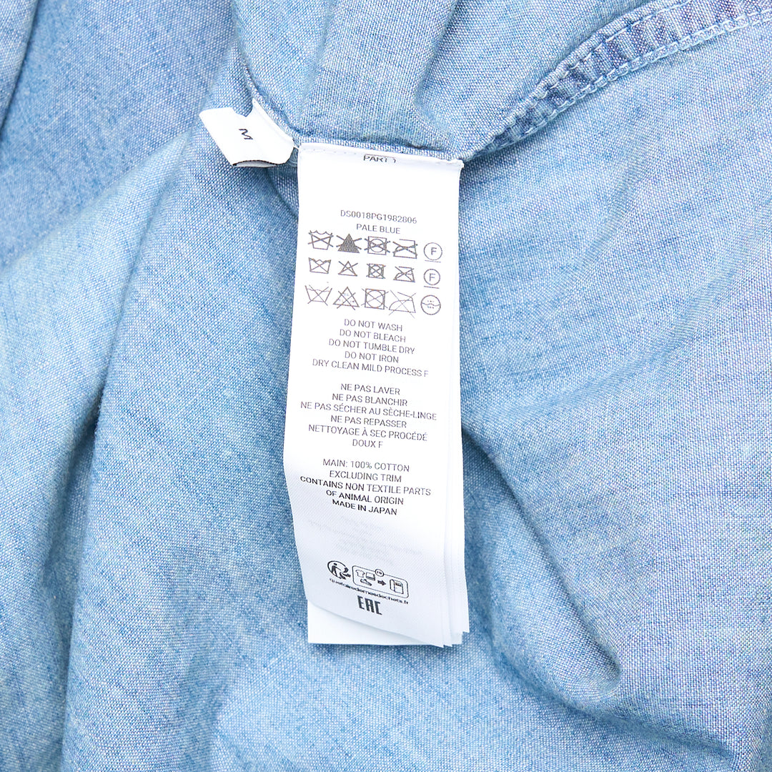 JW Anderson Slant Pocket Chambray Shirt in washed light blue denim, featuring a point collar, button-front closure, and a patch chest pocket