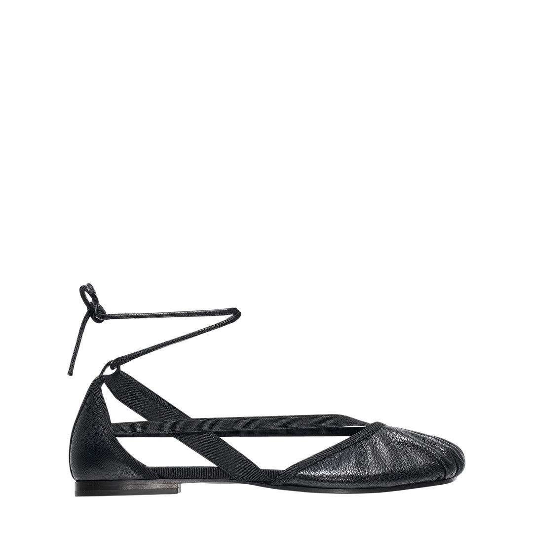 Lemaire Pedille Flat Ballerina in black pebbled goatskin with elasticated cross straps, gathered toe, and ankle-wrap cord tie, shown in profile on a white background
