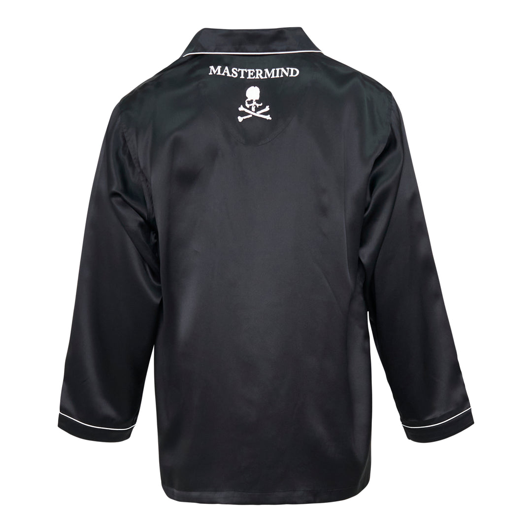 Mastermind black satin pajama set with skull and crossbones embroidery on the chest pocket, white contrast piping trim, button-front long-sleeve top, and relaxed wide-leg trousers