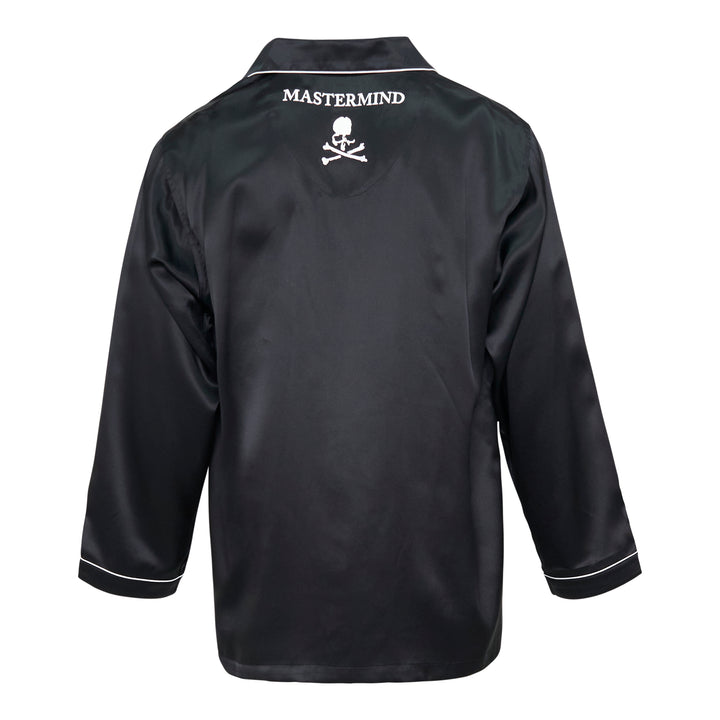 Mastermind black satin pajama set with skull and crossbones embroidery on the chest pocket, white contrast piping trim, button-front long-sleeve top, and relaxed wide-leg trousers