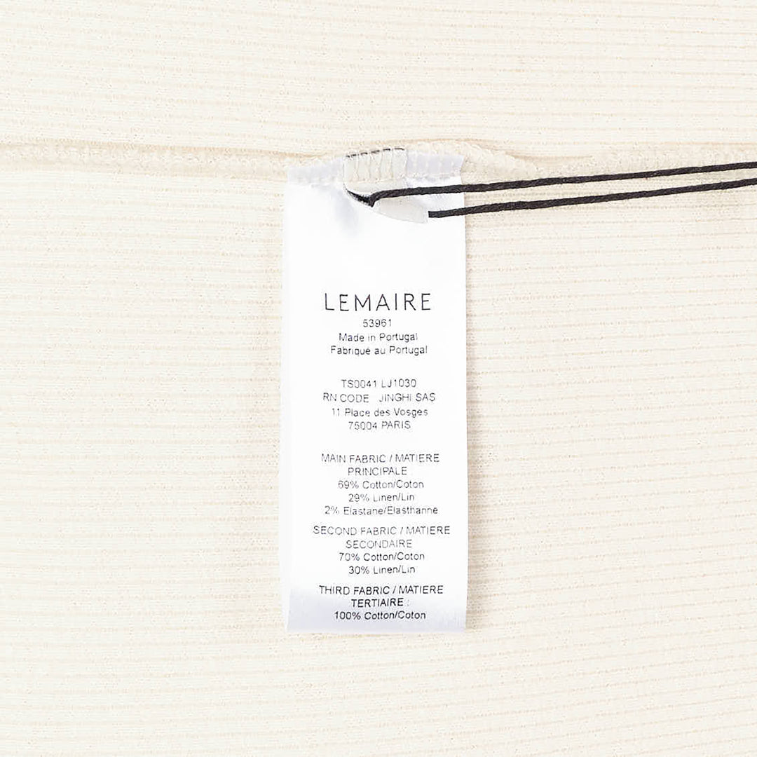 Lemaire long sleeve henley tee in off-white ribbed cotton with a three-button placket and ribbed cuffs, displayed flat on a white background