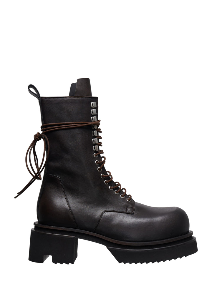Rick Owens Bogun mid-calf lace-up boots in dark washed calf leather, featuring silver hook hardware, wrap-around brown leather lacing with a raw knot, and an exaggerated black lugged platform sole