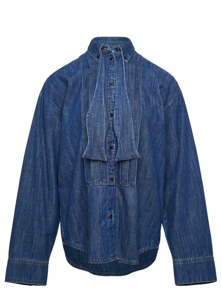 MSGM indigo denim blouse with sculptural attached bowtie bib, button-down collar, full button placket, and wide double cuffs, displayed flat on a white background