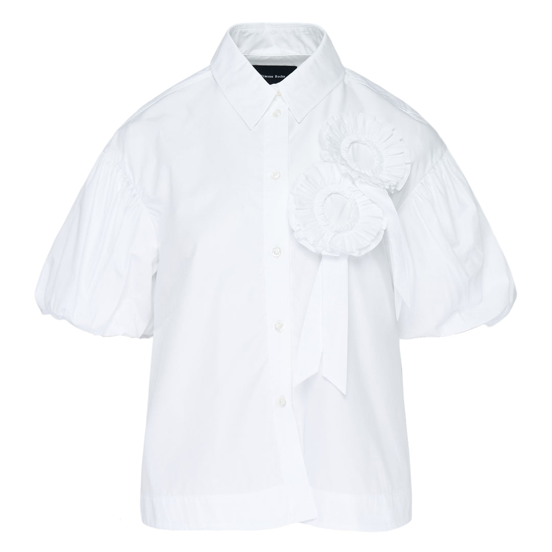 Simone Rocha white cropped blouse with voluminous pleated puff sleeves and an oversized 3D rosette corsage with ribbon detail on the chest