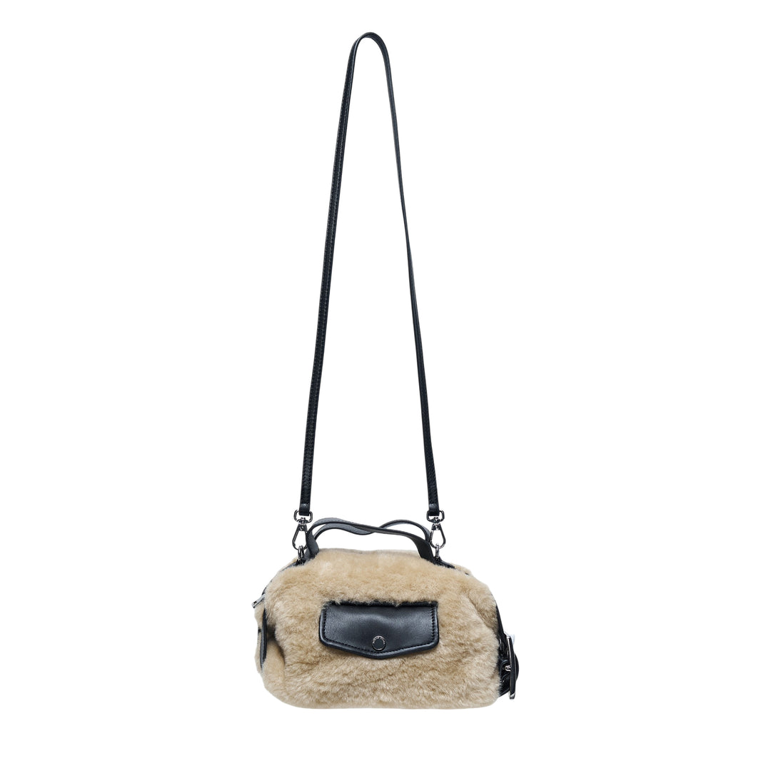Simone Rocha Mini Faux Fur Biker Bag in neutral tan with black leather handles, front snap-closure pocket, and adjustable crossbody strap with silver-tone hardware