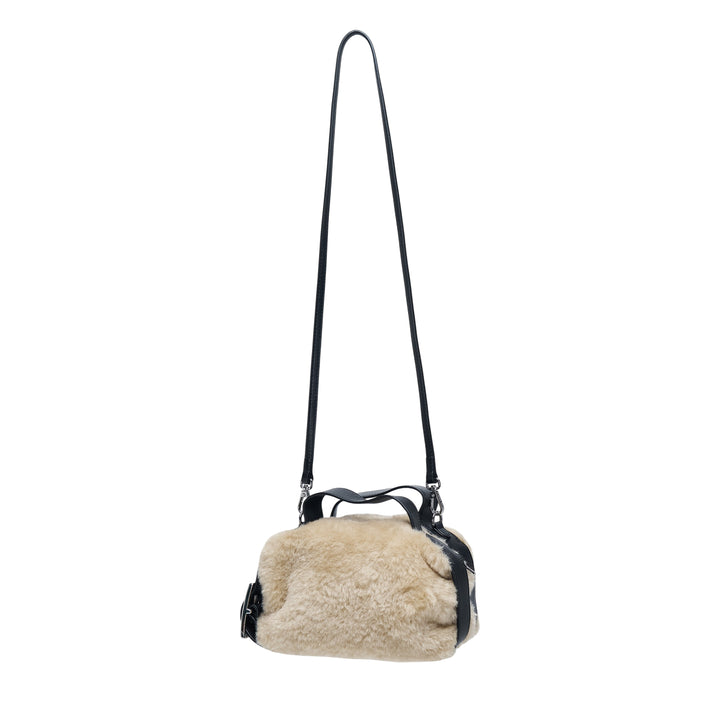 Simone Rocha Mini Faux Fur Biker Bag in neutral tan with black leather handles, front snap-closure pocket, and adjustable crossbody strap with silver-tone hardware