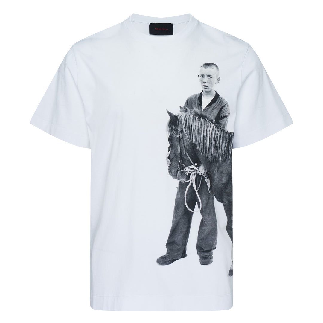 Simone Rocha white oversized short-sleeve tee featuring a black-and-white photographic print of a young boy standing with a pony, with a woven label at the inner back neck