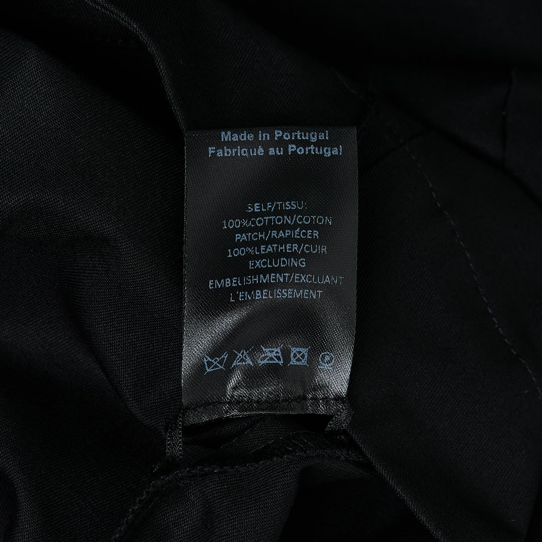 Simone Rocha black cotton twill military overshirt, front view, featuring dual flap chest pockets, tonal button-front closure, and a relaxed oversized silhouette