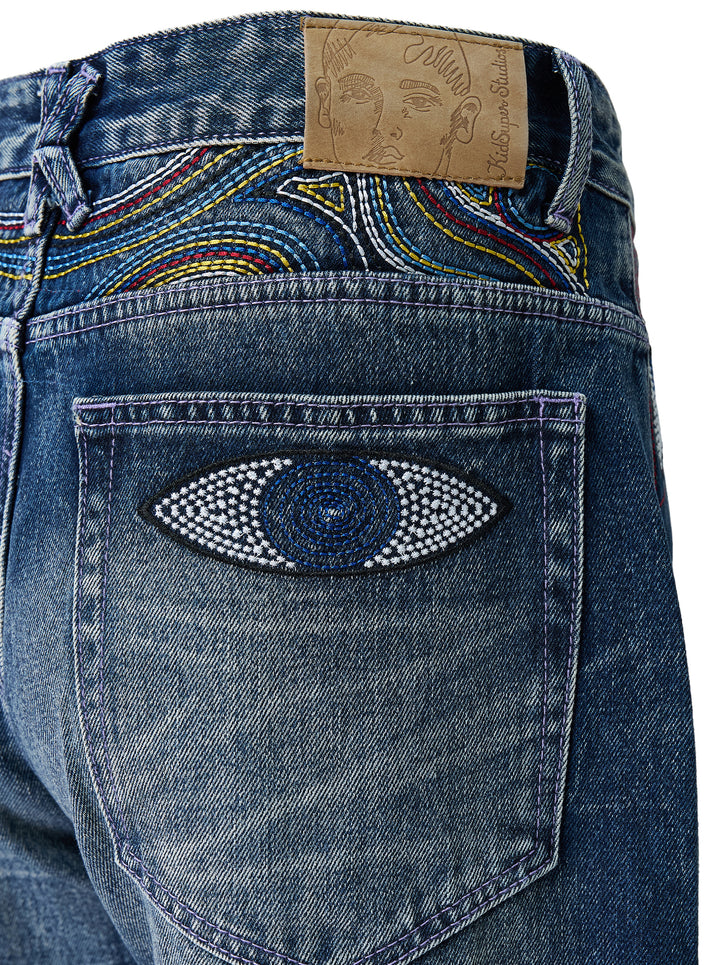 KidSuper Studios Gemstone Eye Embroidery Jeans in faded indigo denim with beaded eye embroidery along both outer legs, shown from the front - view 3