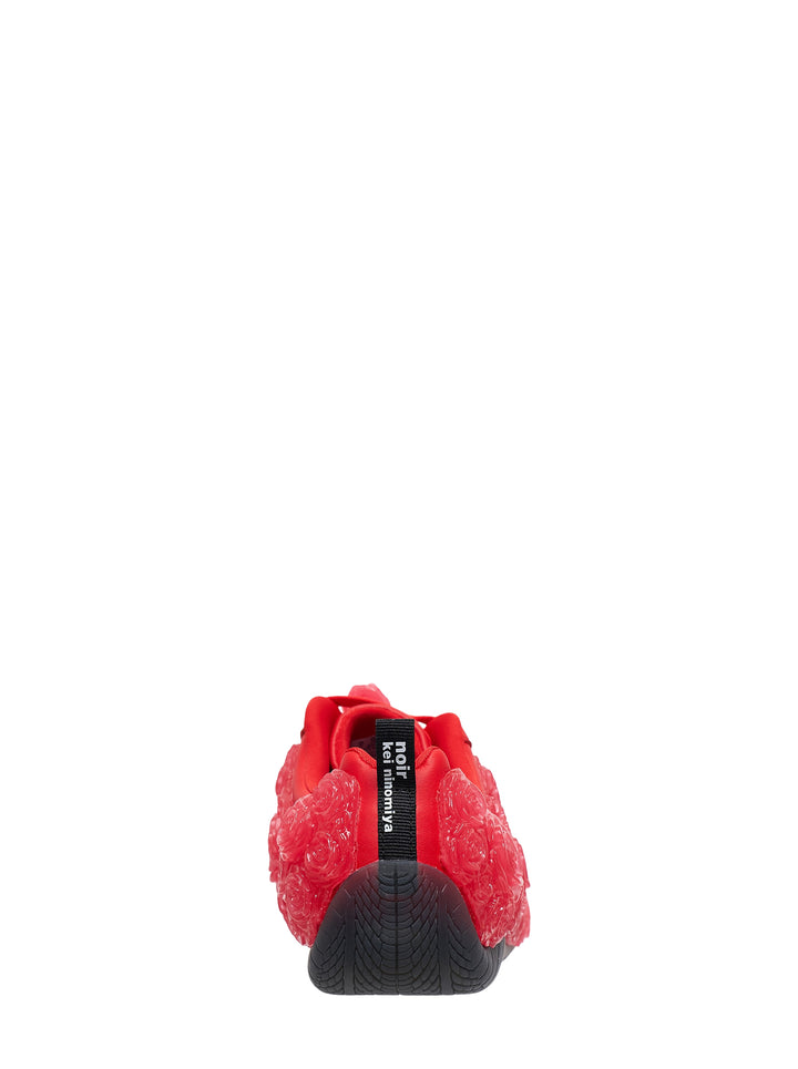 Noir Kei Ninomiya red low-top sneaker with translucent embossed rose details, rose-shaped lace toggles and a black rubber sole, shown in side profile - view 3