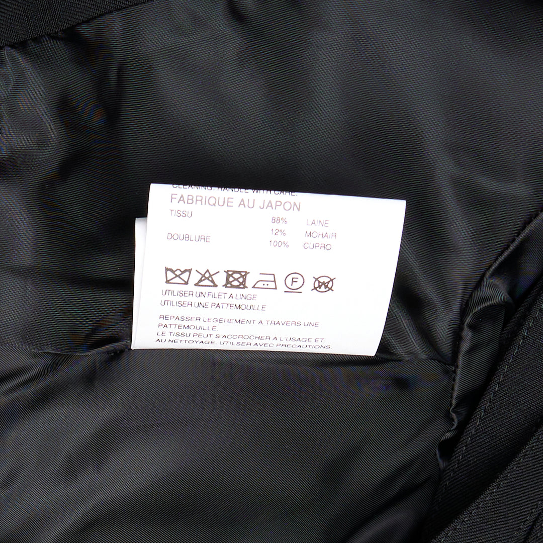 Noir Kei Ninomiya black cropped jacket with horizontal slashed front panels, sculptural shoulders, and double-breasted button detailing, displayed flat on a white background