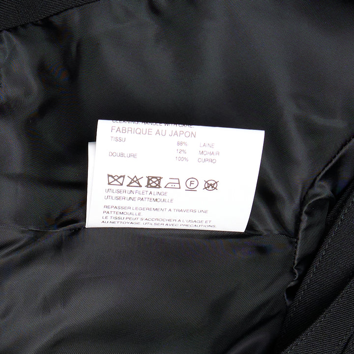 Noir Kei Ninomiya black cropped jacket with horizontal slashed front panels, sculptural shoulders, and double-breasted button detailing, displayed flat on a white background