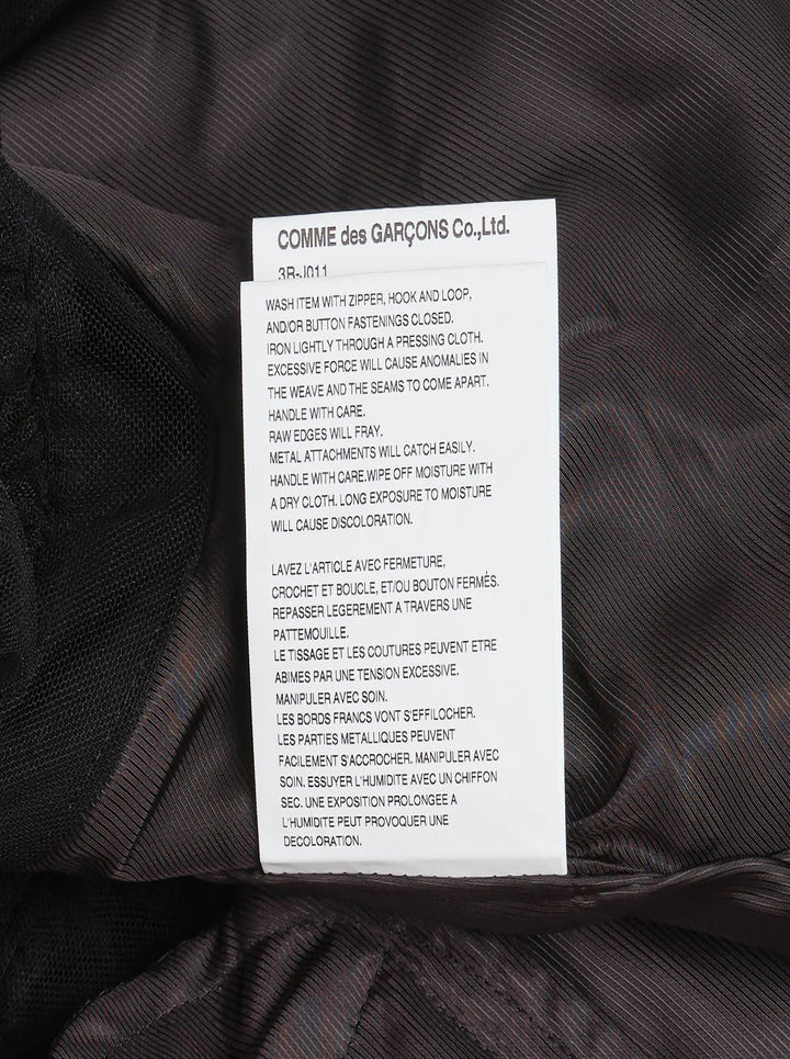 Noir Kei Ninomiya black oversized long sleeve jacket with high drawstring neck, silver zip closures, angled chest zip pockets, and layered black tulle ruffle hem, displayed flat on a white background - view 4