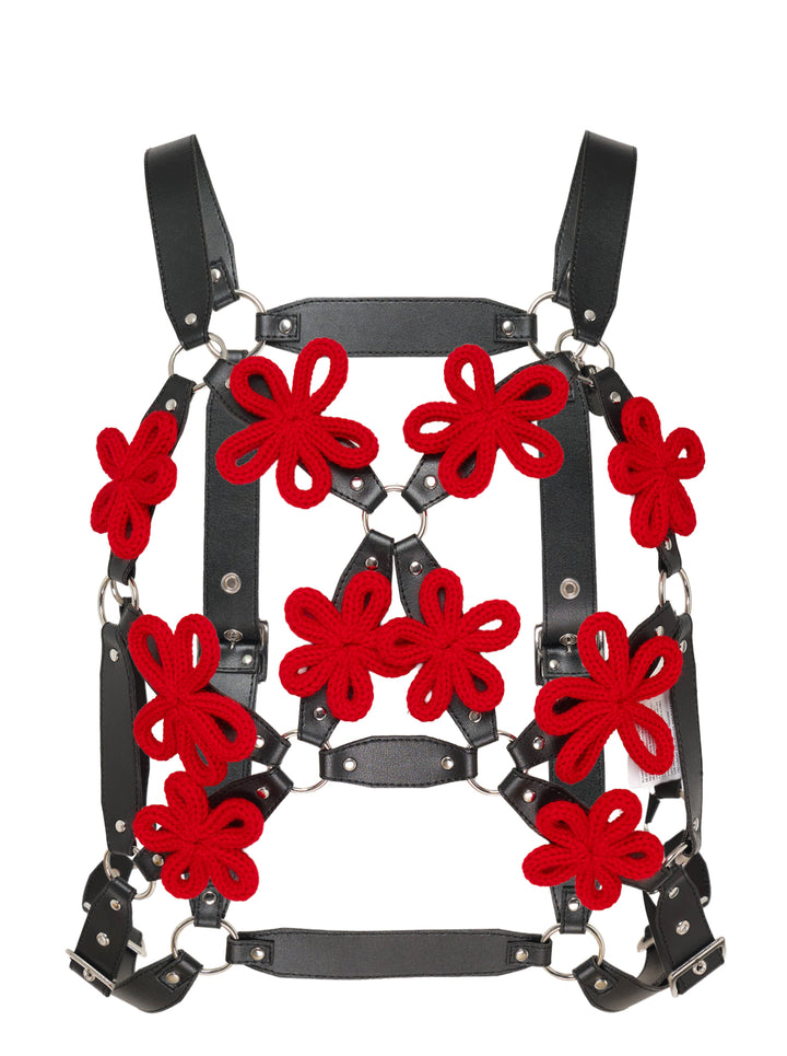Black faux leather harness vest with red knitted floral appliqués, silver ring connectors and adjustable buckles by Noir Kei Ninomiya