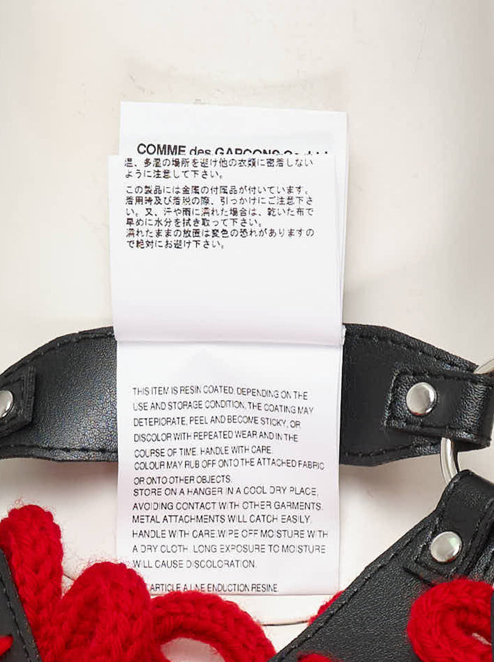 Black faux leather harness vest with red knitted floral appliqués, silver ring connectors and adjustable buckles by Noir Kei Ninomiya - view 4