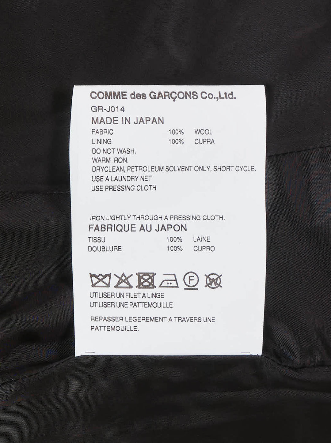Comme des Garçons black wrap blazer with asymmetric curved hem panel exposing satin lining, peak lapels, jewel-set buttons, and structured shoulders, displayed flat on white background - view 3