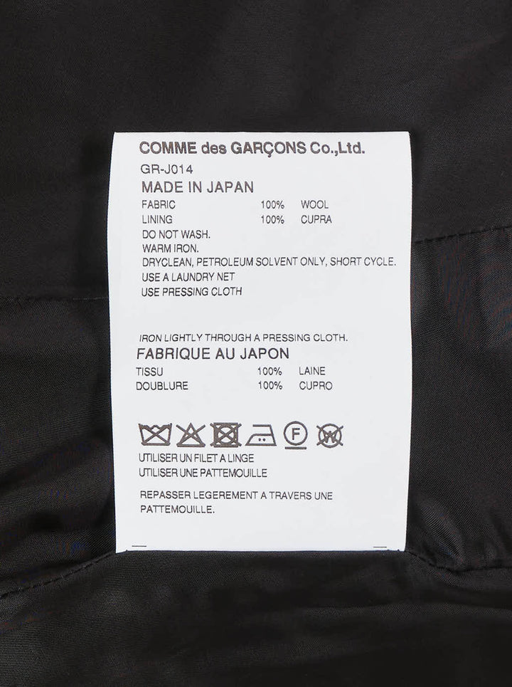 Comme des Garçons black wrap blazer with asymmetric curved hem panel exposing satin lining, peak lapels, jewel-set buttons, and structured shoulders, displayed flat on white background - view 3