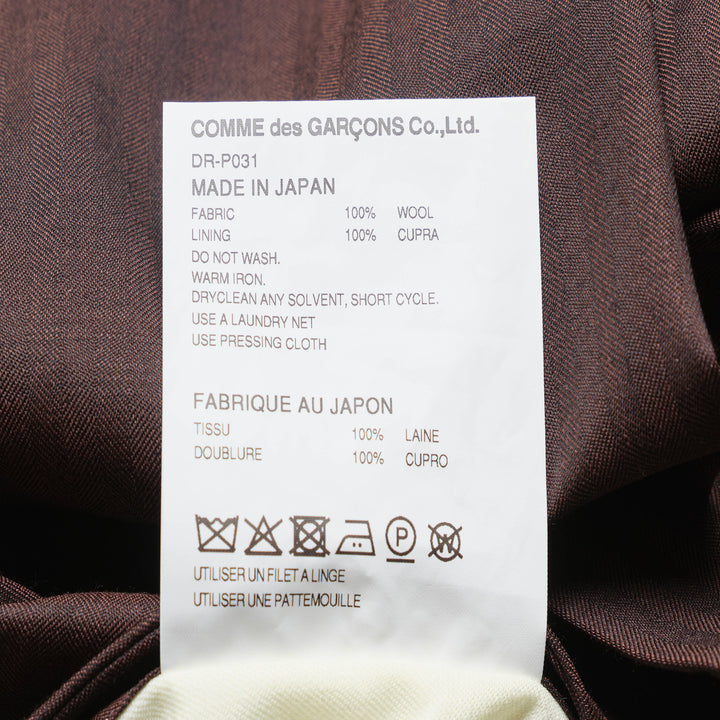 Comme des Garçons Homme Deux wool mini herringbone pants in brown, featuring a tapered leg, elasticated waistband, and panelled knee construction, shown flat on a white background - view 3