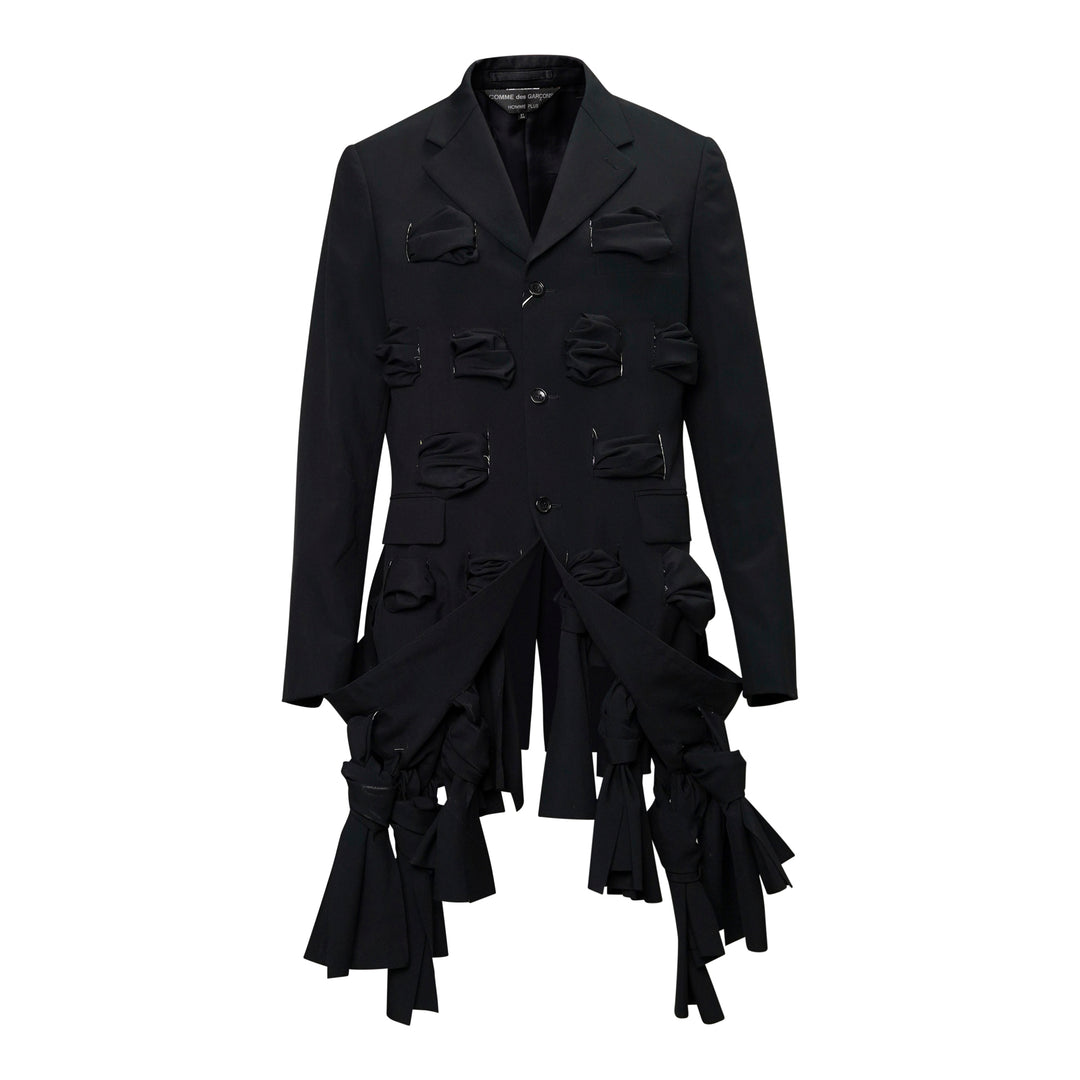 Comme des Garçons Homme Plus black tropical wool single-breasted jacket with gathered fabric loop appliqués across the body and cascading deconstructed strip detailing at the hem, front view on white background