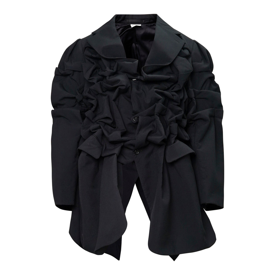 Comme des Garçons Homme Plus black wool tropical jacket with dramatic sculptural ruffles cascading across the chest and shoulders, long sleeves, and a notched lapel collar, displayed on a white background