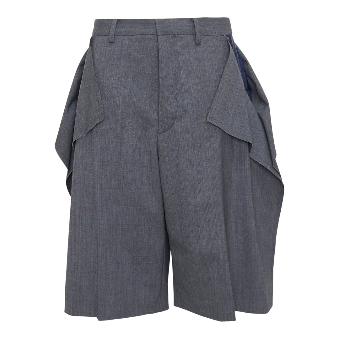 Undercover grey wool-blend tailored shorts with oversized draped side flaps revealing navy lining, featuring belt loops, pleated front, and concealed zip fly