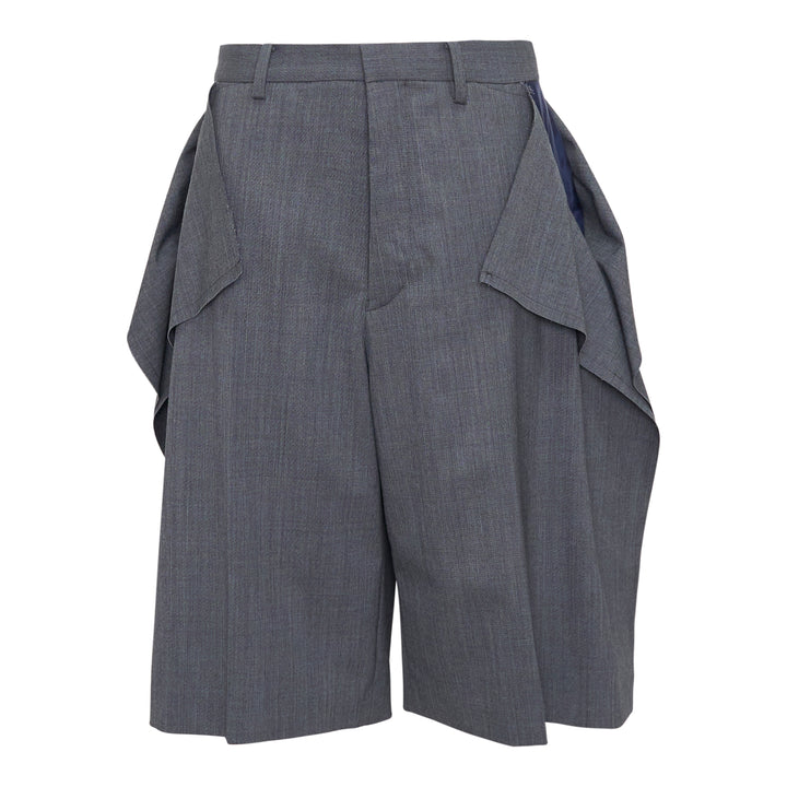 Undercover grey wool-blend tailored shorts with oversized draped side flaps revealing navy lining, featuring belt loops, pleated front, and concealed zip fly