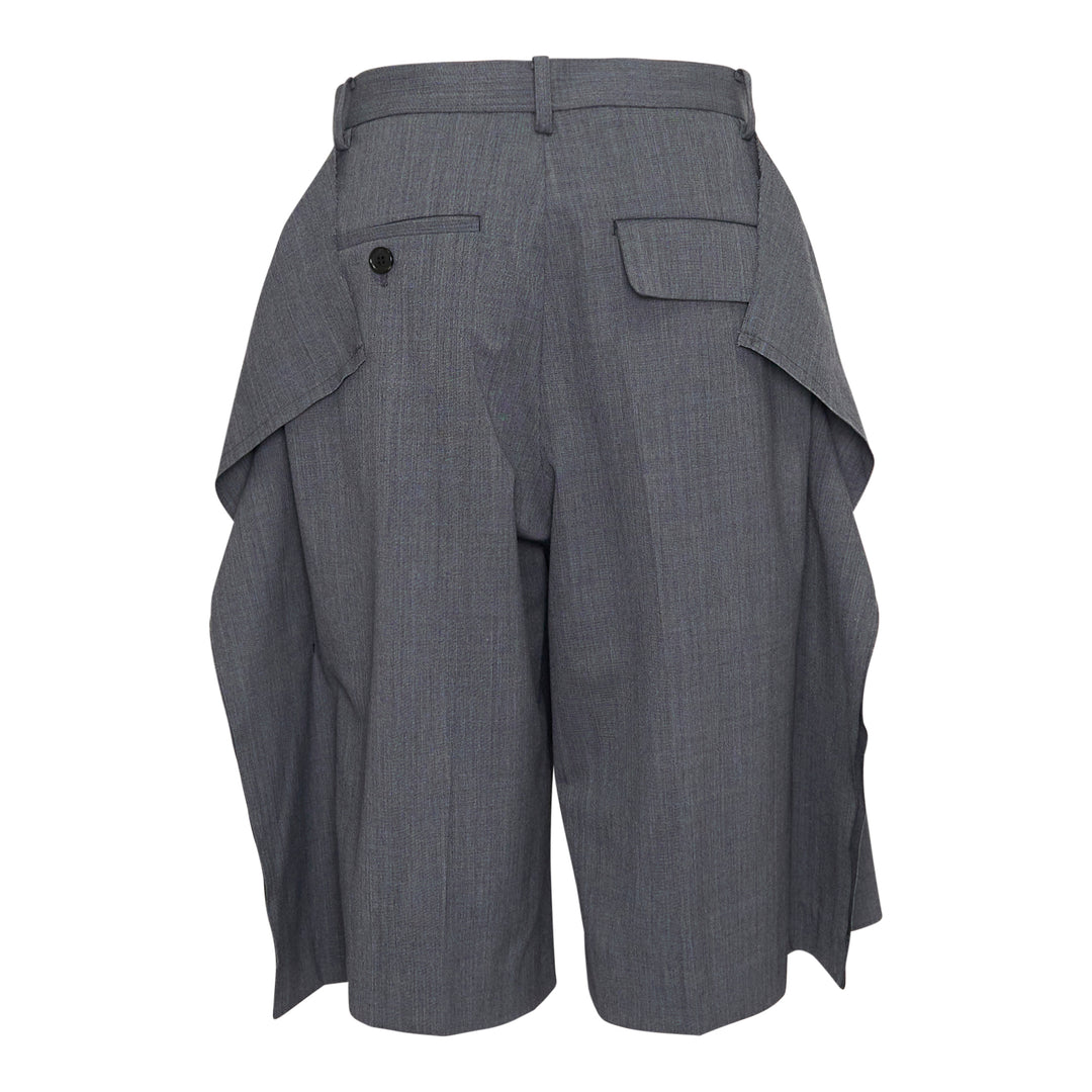 Undercover grey wool-blend tailored shorts with oversized draped side flaps revealing navy lining, featuring belt loops, pleated front, and concealed zip fly