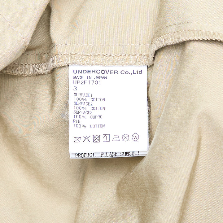Undercover Trompe L'Oeil Sweater Dress featuring a navy raglan sweatshirt top with small embroidered chest motif over a khaki twill midi skirt with front vent and patch pocket, presented as a single garment