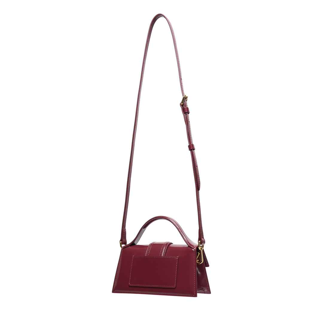 Jacquemus Le Bambino Shiny mini shoulder bag in burgundy high-shine leather with gold logo lettering, top handle, and adjustable crossbody strap - view 2
