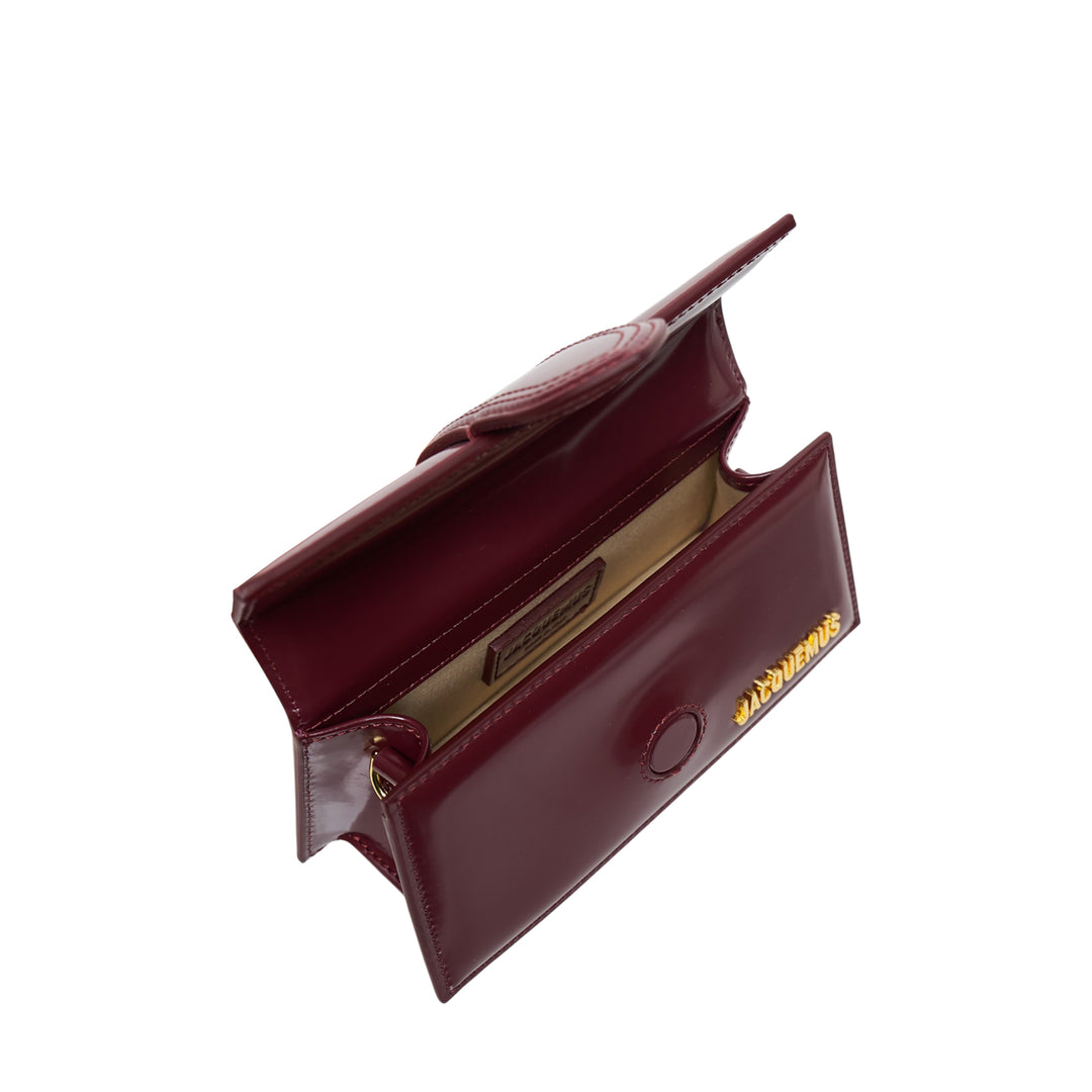 Jacquemus Le Bambino Shiny mini shoulder bag in burgundy high-shine leather with gold logo lettering, top handle, and adjustable crossbody strap - view 3