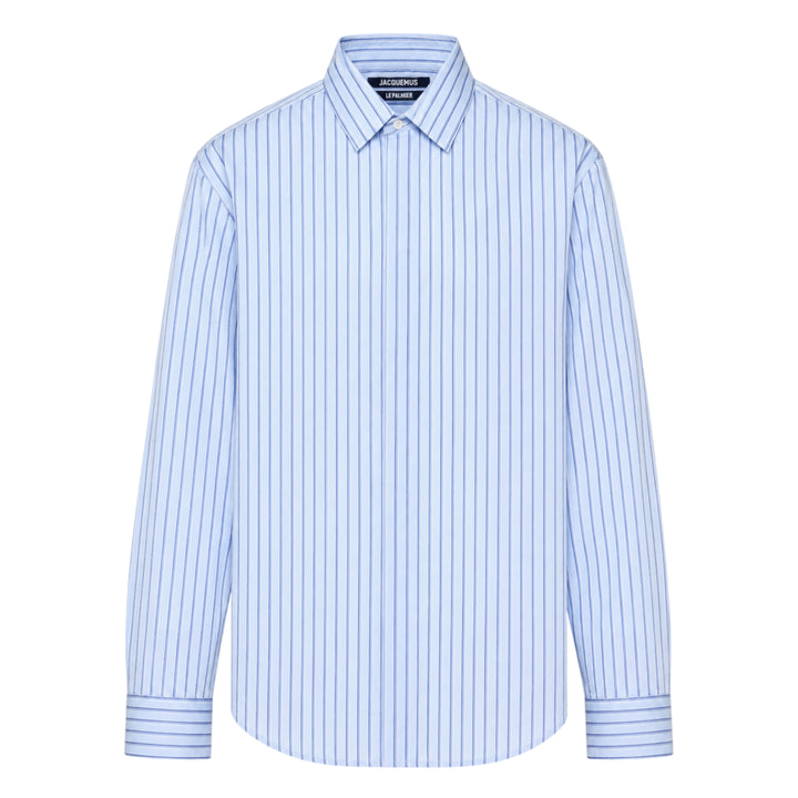 Jacquemus La Chemise Simon long sleeve shirt in light blue with navy vertical pinstripes, featuring a classic point collar and double-button barrel cuffs