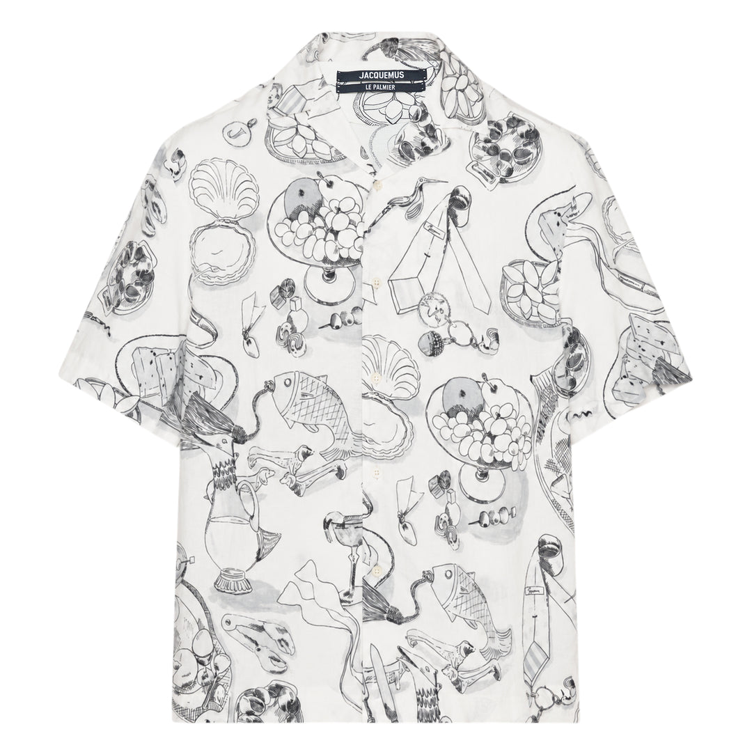 Jacquemus La Chemise Cocktail short sleeve shirt in white with an all-over monochrome hand-drawn still-life sketch print featuring shells, fish, fruit, and ribbon motifs, camp collar, and button-through front fastening