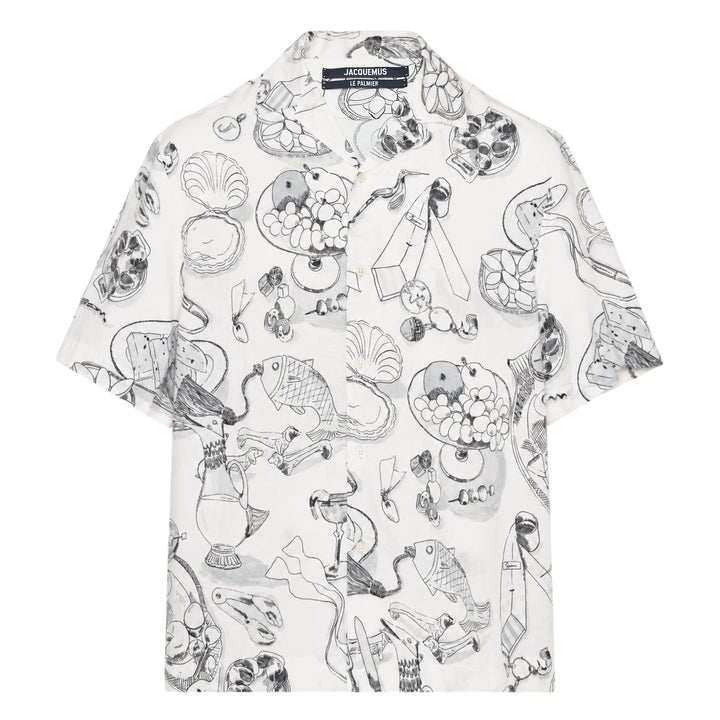 Jacquemus La Chemise Cocktail short sleeve shirt in white with an all-over monochrome hand-drawn still-life sketch print featuring shells, fish, fruit, and ribbon motifs, camp collar, and button-through front fastening