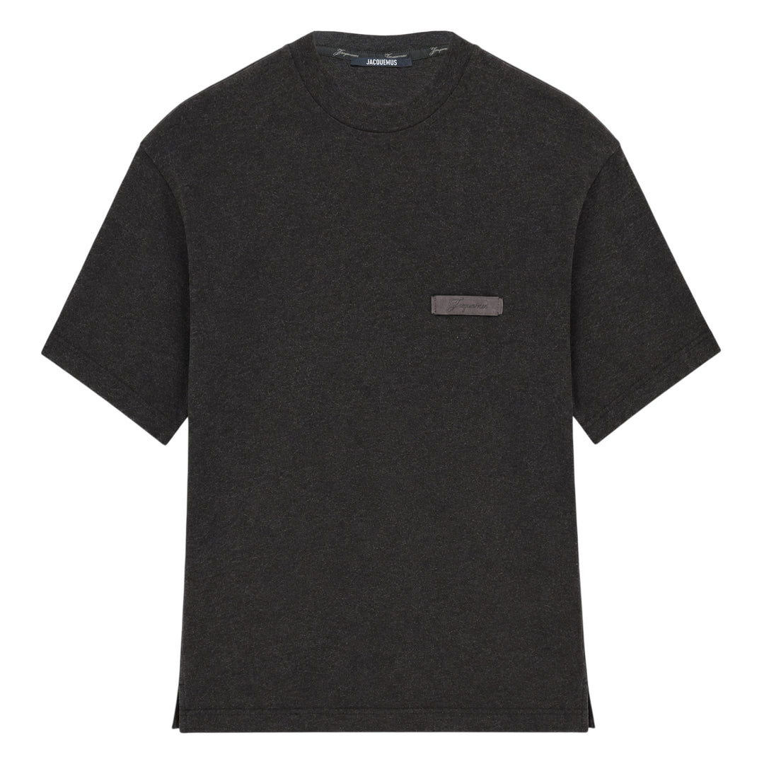 Jacquemus Le T-Shirt Ruban in charcoal grey, featuring a boxy silhouette, crew neckline, and a tonal signature woven label patch at the chest