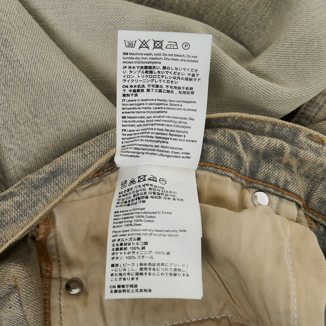 Our Legacy Third Cut Jeans in a heavily faded sandy beige wash with blue tonal shifts, featuring a high-rise waist, straight leg and cropped flare hem, shown flat on a white background