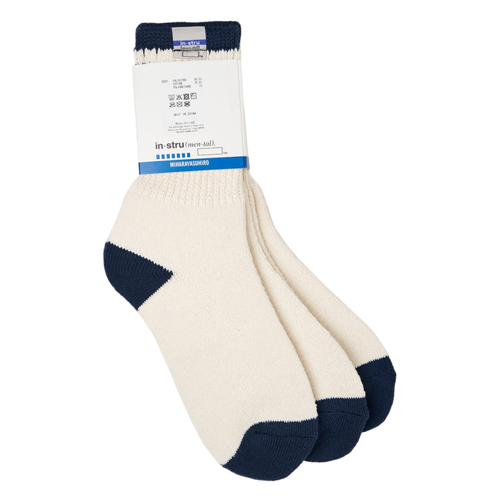 Mihara Yasuhiro three-pack crew socks in off-white with navy contrast cuff, heel, and toe, displayed fanned with branded 'Ready to Wear' sole print visible and original hangtag attached - view 2