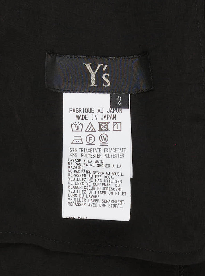 Y's black halter apron jumpsuit with an asymmetric draped bib and wide-leg silhouette, shown from the front - view 3