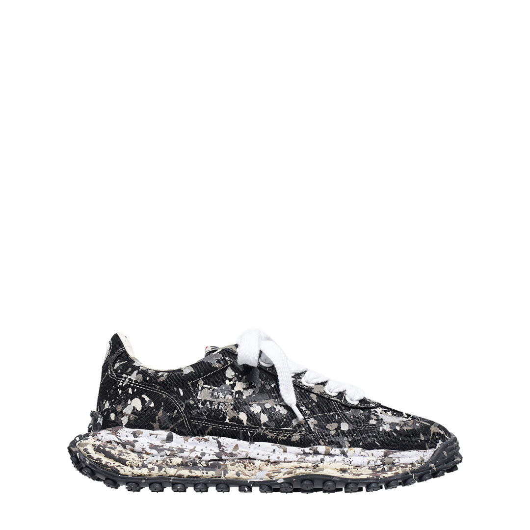 Mihara Yasuhiro Larry low-top sneaker in black canvas with white and grey paint-splatter sputtering finish across the upper and midsole, styled with flat white laces and a chunky lugged rubber outsole
