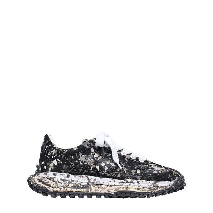 Mihara Yasuhiro Larry low-top sneaker in black canvas with white and grey paint-splatter sputtering finish across the upper and midsole, styled with flat white laces and a chunky lugged rubber outsole