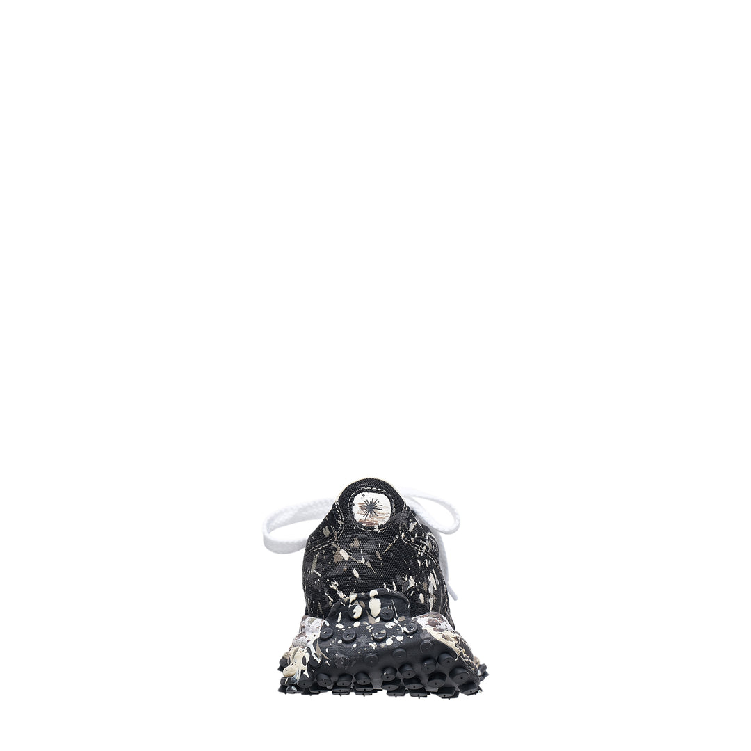 Mihara Yasuhiro Larry low-top sneaker in black canvas with white and grey paint-splatter sputtering finish across the upper and midsole, styled with flat white laces and a chunky lugged rubber outsole